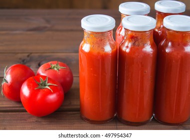 bottles of homemade ketchup and tomatoes on old wood. tomato sauce