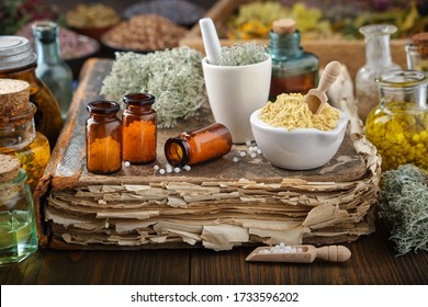 Bottles of homeopathic drugs, mortars of mineral substances and medicinal plants. Infusion bottles and healing herbs on background. Homeopathy medicine. 