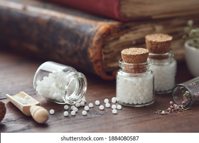 Bottles of homeopathic globules and old books. Homeopathy medicine concept.