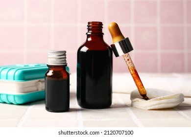 Bottles with iodine, pipette, cotton pads and first aid kit on tile background