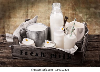 Bottles And Jars With Fresh Milk Products In Old Wooden Crate With Gunny Sack On Old Used Background