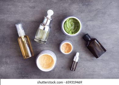 Bottles And Jars With Natural Skincare Cosmetics, Creams And Oils On Dark Background. Plant-based Beauty Products. Top View