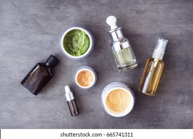 Bottles and jars with natural skincare cosmetics, creams and oils on dark background. Plant-based beauty products. Top view