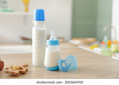 Bottles of milk for baby with toys on table in kitchen