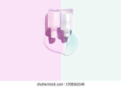 Bottles Of Pink And Mint Blue Nailpolish With Shadow And Spill On Color Block Background