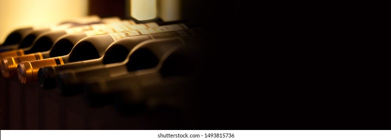 Bottles Of Red Wine On A Wooden Shelf, Panoramic Banner With Black Background