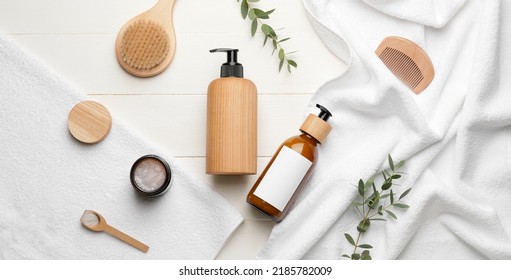Bottles of shampoo, comb, towels and brush on white wooden background, top view - Shutterstock ID 2185782009
