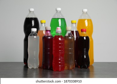 Bottles Of Soft Drinks On Table Against Grey Background