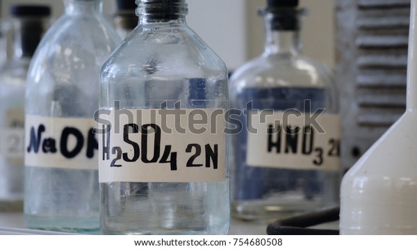 Bottles of solutions stored on shelf in laboratory. Bottles with chemical solutions of NaOH, H2so4 and HNO3. Sulfuric acid, sodium hydroxide, nitric acid