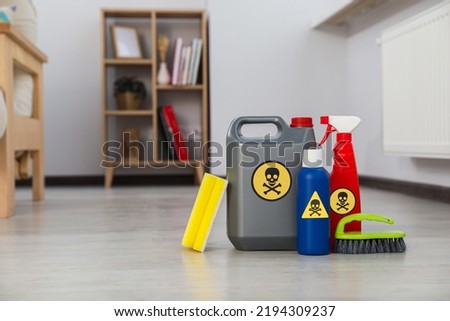 Bottles of toxic household chemicals with warning signs, brush and scouring sponge in room, space for text