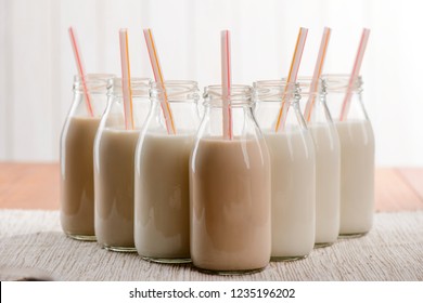 Bottles of vegan milk with straws. Creamy plant-based drinks made of organic ingredients, alternative to cow's milk.