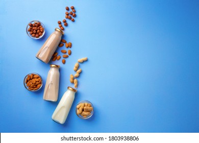 Bottles of vegan non dairy milk with various nuts on blue background - Shutterstock ID 1803938806