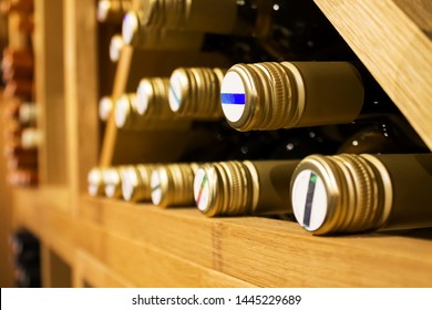 Bottles Of White Wine With Golden Colored Wrap Laying Down On The Wooden Shelf In Dark,fresh Cellar