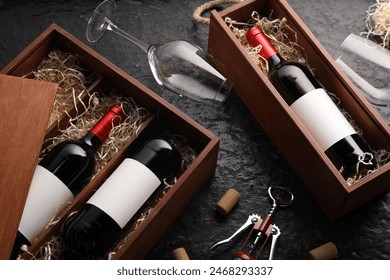 Bottles of wine in wooden boxes, glasses, corkscrew and corks on dark textured table, above view