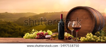 Bottles And Wineglasses With Grapes And Barrel On A Sunny Background. Italy Tuscany
