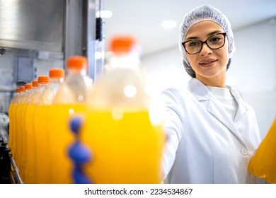 Bottling factory interior and female worker checking orange juice production. - Powered by Shutterstock