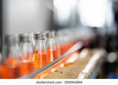 Bottling factory. Bottling line for processing and bottling Basil seed with fruit into bottles. Product of Basil seed with Pomegranate on the conveyor belt in the beverage factory - Powered by Shutterstock