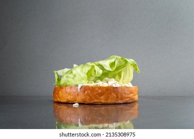 Bottom Burger Bun On A Stainless Steel Table. Assemble A Burger With A Lettuce Leaf On The Bun.