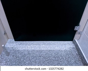 Bottom Of The Door From Inside A Public Toilet Cubicle, With Light Shining Through The Gap At The Bottom