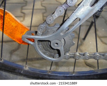 Bottom gear of mountain bike derailleur with chain and orange reflector in the background.