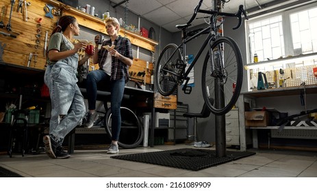 Bottom of girls have lunch with coffee and sandwiches and talk in bicycle workshop. Young multiracial cycling female mechanics. Friendship. Bike service, repair and upgrade. Rest and break at work - Powered by Shutterstock