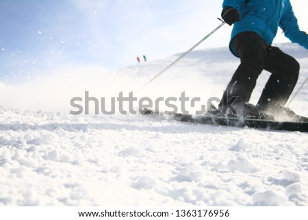 bottom half of skiier coming down mountain spraying snow