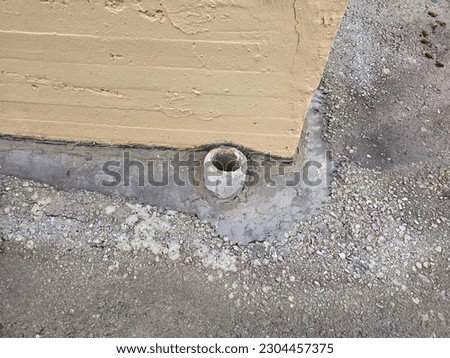 The bottom of a large drain against a b uilding.