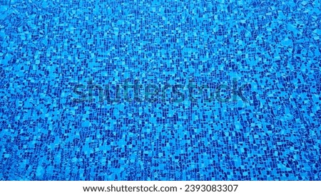 The bottom of a motley swimming pool made of multi-colored tiles under a layer of water