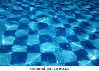 Bottom Of A Pool With Some Drops Of Condensation In The Water And Some Ripple In A Beatiful Visual Efect. Background Chess Square Checker On Dark Blue Alternated With Light Blue And Artistic Strokes.