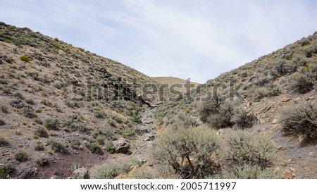 The bottom of rocky desert wash, surrounded by brown dirt and sagebrush.