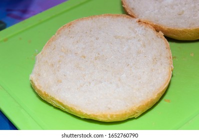 The Bottom Of A Round Burger Bun On A Cutting Board.