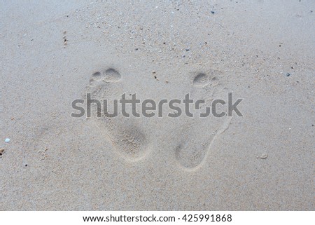 bottom of sand with two marked prints of feet