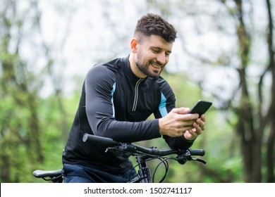 Bottom and side view of bicyclist on bike using navigator on smart phone, explore map and search GPS coordinates while biking in mountains.
