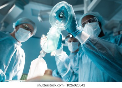 bottom view of african american anesthetist holding oxygen mask above patient in surgery room