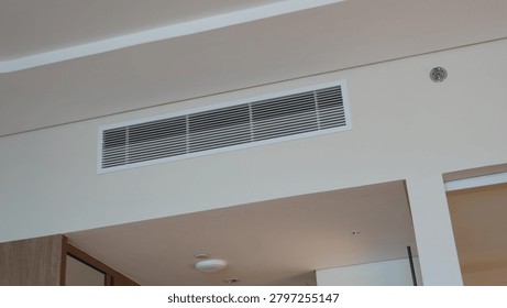From bottom view of air conditioning wall mounted ventilation system on ceiling in white clean hotel guest room background. Hotel room air ventilation grill on the wall.