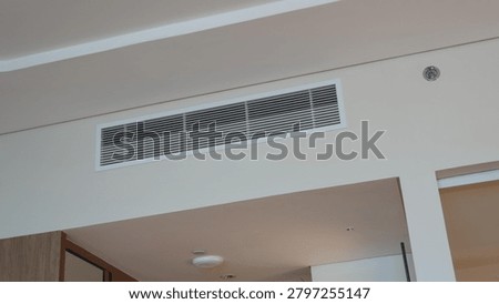 From bottom view of air conditioning wall mounted ventilation system on ceiling in white clean hotel guest room background. Hotel room air ventilation grill on the wall.