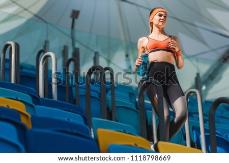 bottom view of attractive young woman walking on stairs at sports stadium