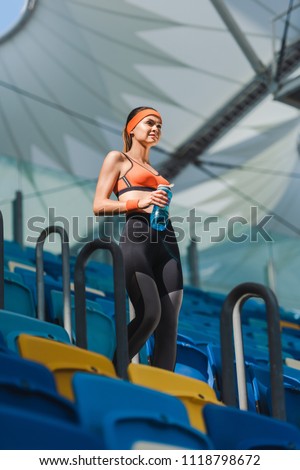 bottom view of beautiful young woman walking on stairs at sports stadium