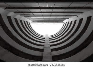 Bottom view of circular car parking garage against white clouds and blue sky. Automated circular parking system. Abstract architecture building. - Powered by Shutterstock