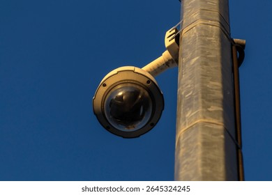 Bottom view of dome security camera mounted on a metal pole against a blue sky in Brazil Surveillance system for public safety