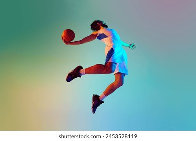 Bottom view dynamic image of young man, basketball player in motion, throwing ball against gradient background in neon light. Concept of sport, competition, active and healthy lifestyle, game - Powered by Shutterstock