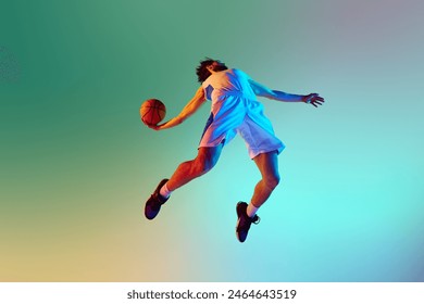 Bottom view dynamic image of young man, basketball player in motion, throwing ball against gradient background in neon light. Concept of sport, competition, active and healthy lifestyle, game - Powered by Shutterstock