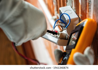 Bottom view. Electrician worker at work with the tester measures the voltage in an electrical system. Working safely with protective gloves. Construction industry.