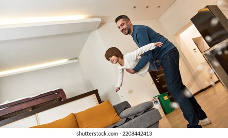 Bottom view of father holding little son flying like bird at home. Young joyful caucasian man and boy enjoying time together. Family relationship. Fatherhood and parenting. Modern domestic lifestyle - Shutterstock ID 2208442413