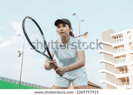 Bottom view of a female tennis athlete concentrating holding racket on the court