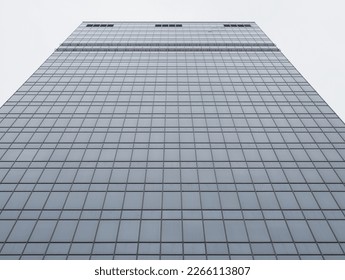 bottom view of flat glass wall of skyscraper on overcast day - Shutterstock ID 2266113807