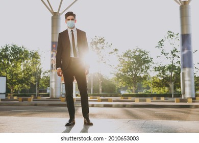 Bottom View Full Body Sunlit Young Traveler Businessman Man Wearing Black Dinner Suit Sterile Mask Stand Outside At International Airport Terminal Look Camera. People Air Flight Business Trip Concept