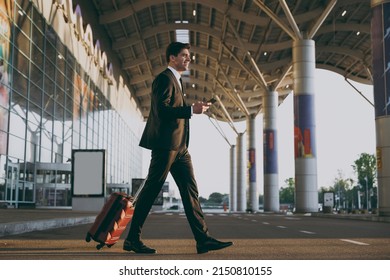 Bottom view full body young traveler businessman man in black suit walk outside at international airport terminal with suitcase use mobile cell phone book taxi order hotel Air flight business concept. - Powered by Shutterstock
