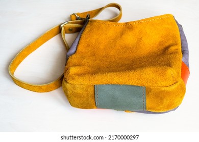 bottom view of handcrafted cross body bag hand sewn from yellow suede on white background