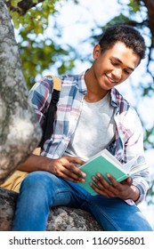 Bottom View Of Happy Teen Student Reading Book Under Tree